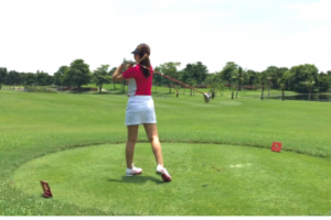 ティーショット後にボールの飛び先を確認する女性ゴルファー